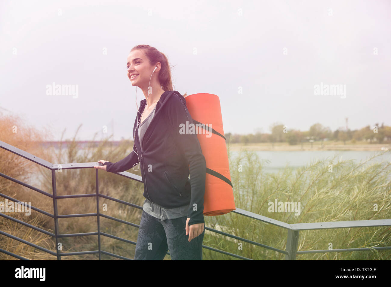 Giovane donna fitness walking con mat sul retro per esterno Foto Stock