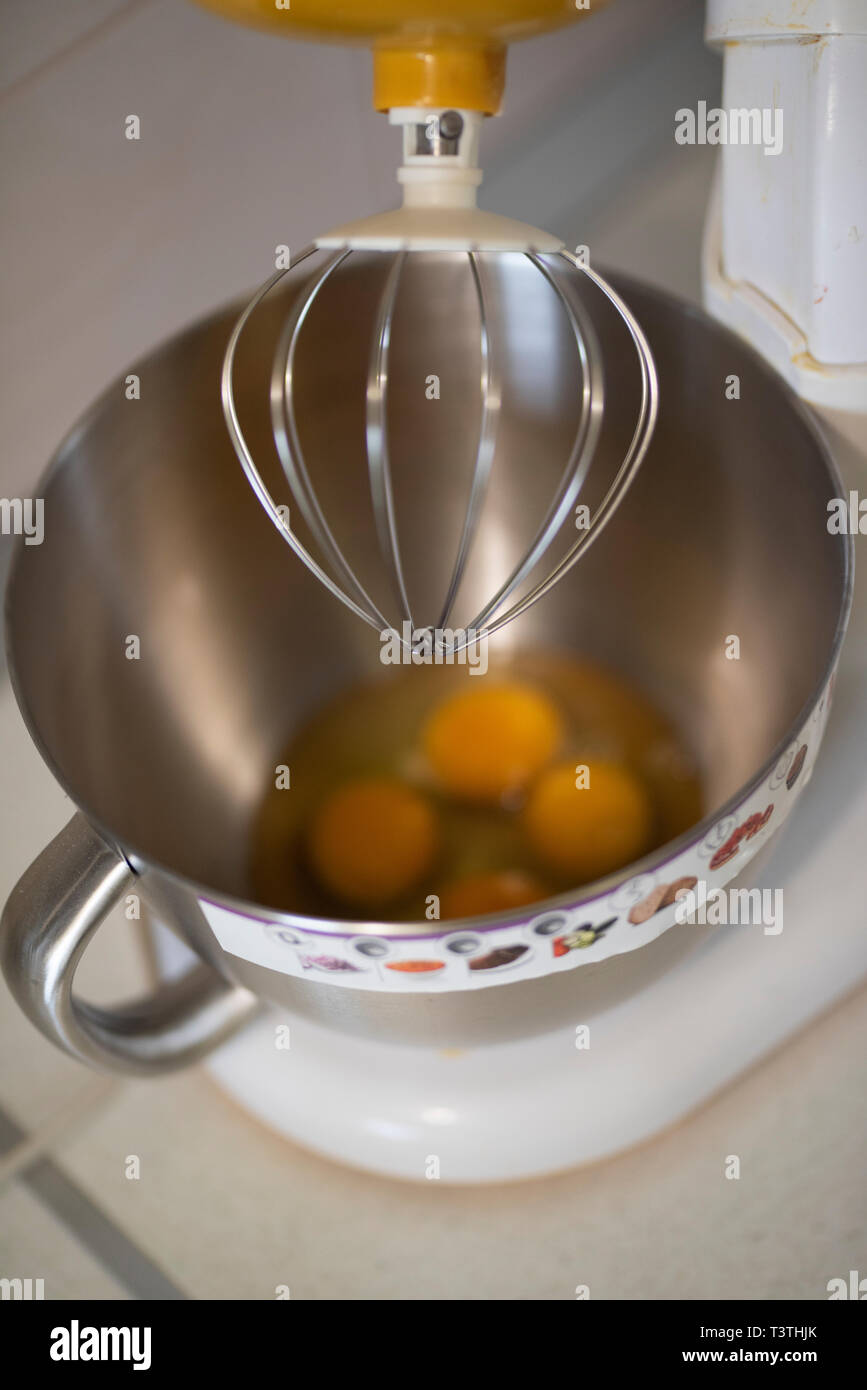 Cucina anteriore con un miscelatore planetario con gli albumi e i tuorli in una ciotola metalic in attesa di essere agitata. Utensili da cucina elettrica ustensil utilizzato per preparare Foto Stock