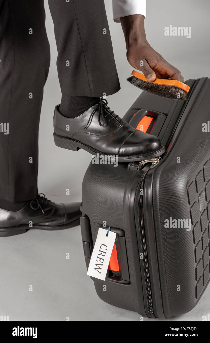 Compagnia aerea spazzolatura pilota il suo nero scarpe uniforme. Foto Stock