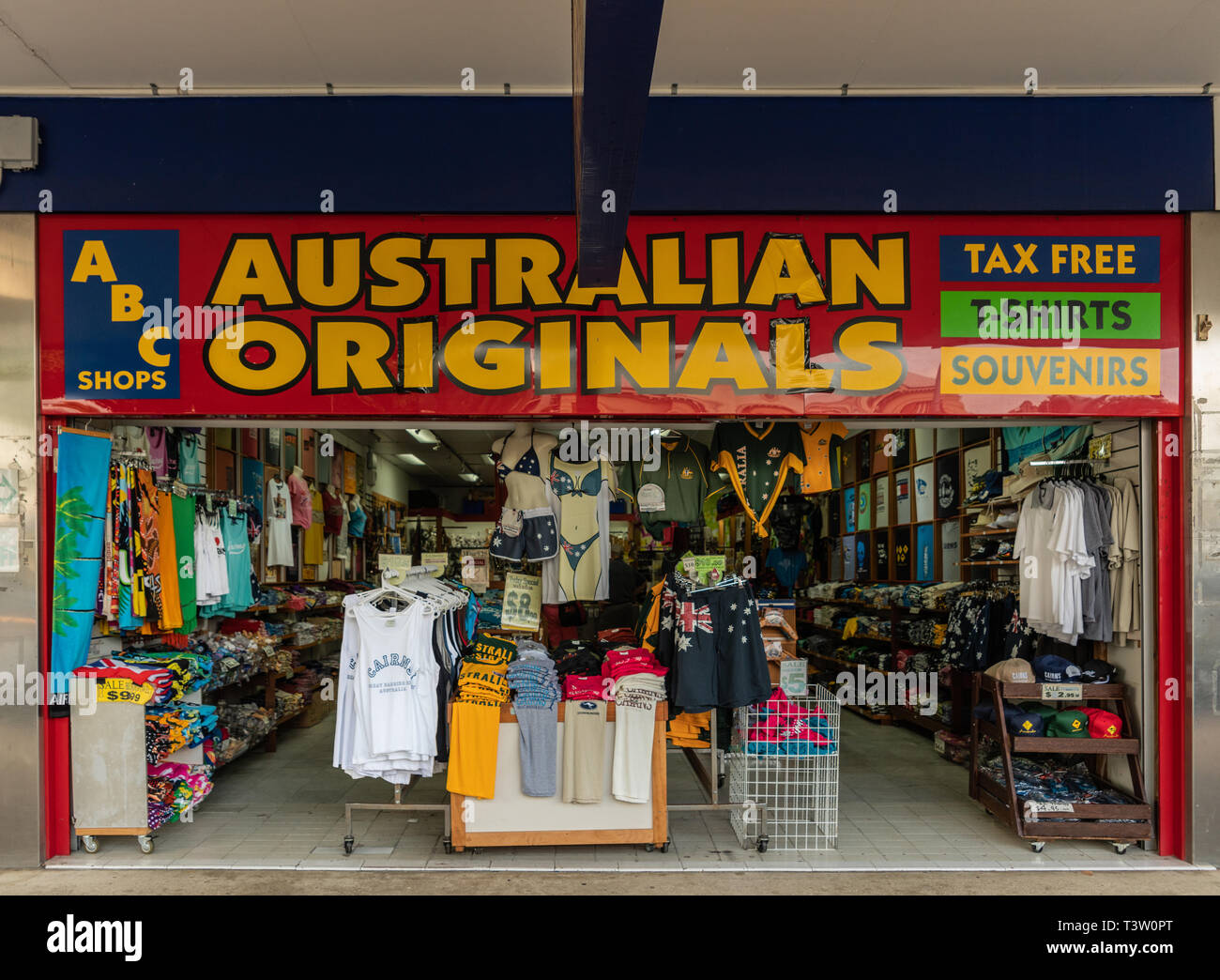 Cairns, Australia - 17 Febbraio 2019: Australian originali souvenir shop con finestra aperta la visualizzazione di T-shirt e altri capi di abbigliamento a basso costo. Giallo su rosso Foto Stock
