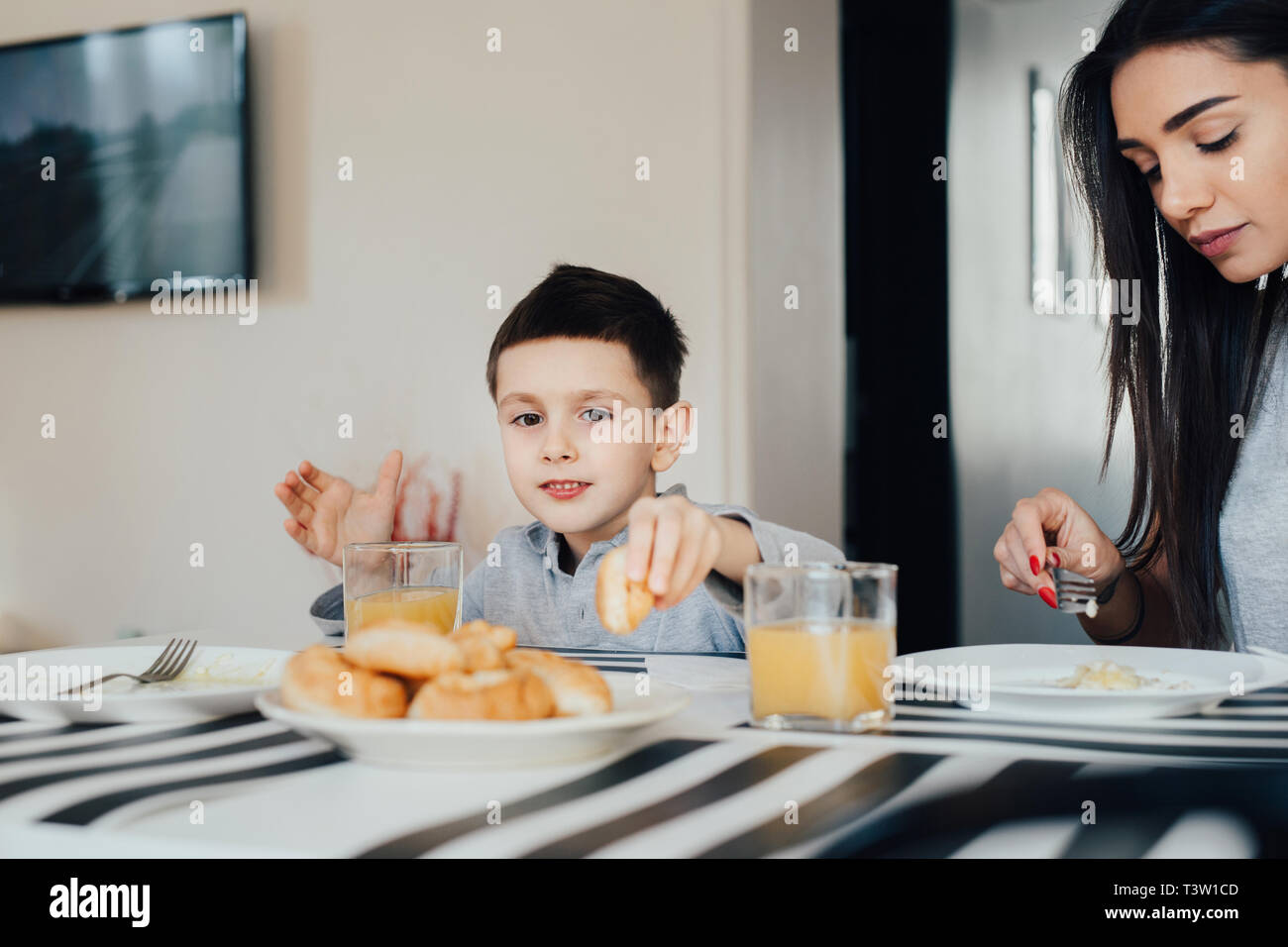 Bella giovane donna a casa con il suo piccolo figlio carino sono avente la prima colazione. Felice Festa della Mamma Foto Stock