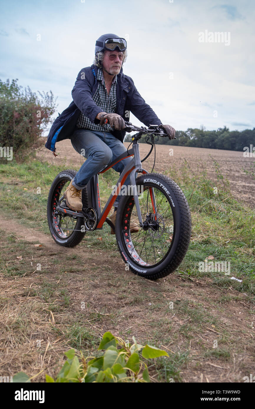 Un uomo che cavalca un Volt Bigfoot bicicletta elettrica UK Foto Stock