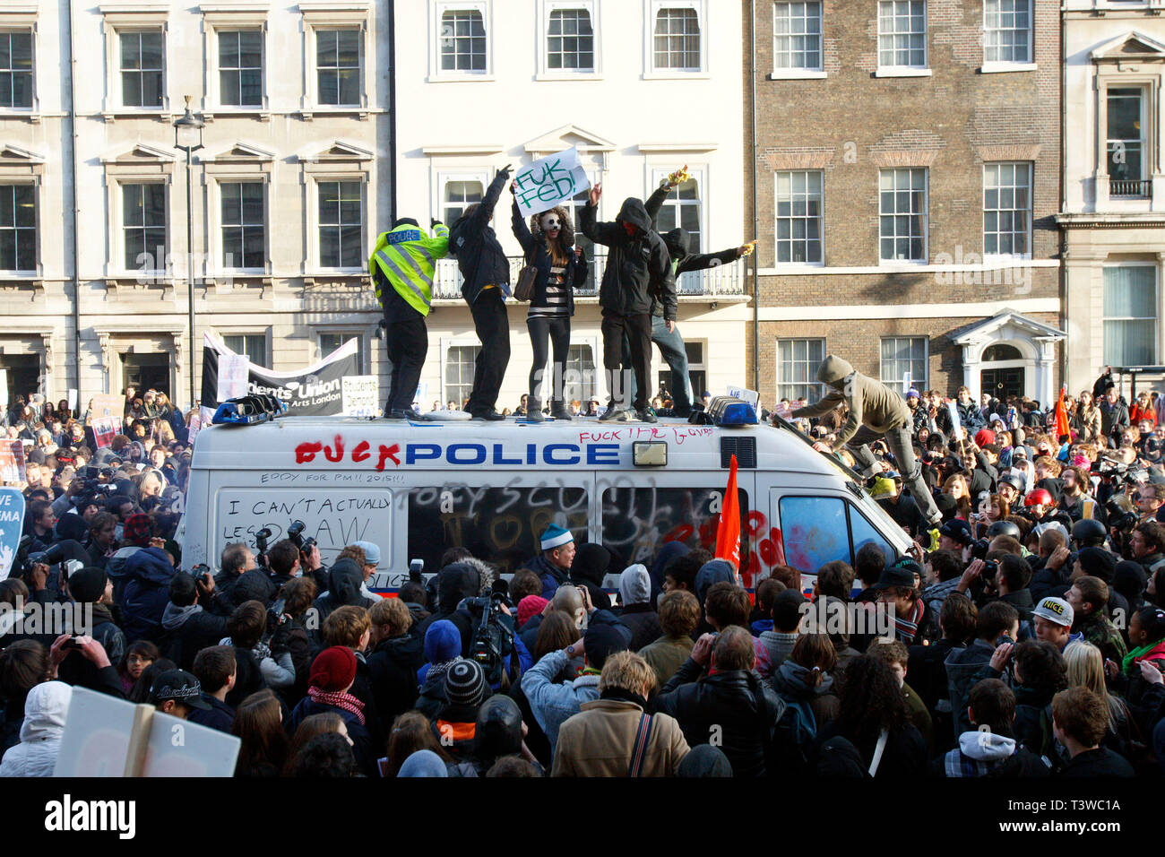 Un manifestante sorge sul vetro fracassato di una polizia van. Gli studenti protestano contro piallato alzare le tasse e tagli al finanziamento delle università. Lond Foto Stock Un manifestante sorge sul vetro fracassato di una polizia van. Gli studenti protestano contro piallato alzare le tasse e tagli al finanziamento delle università. Lond Foto Stock