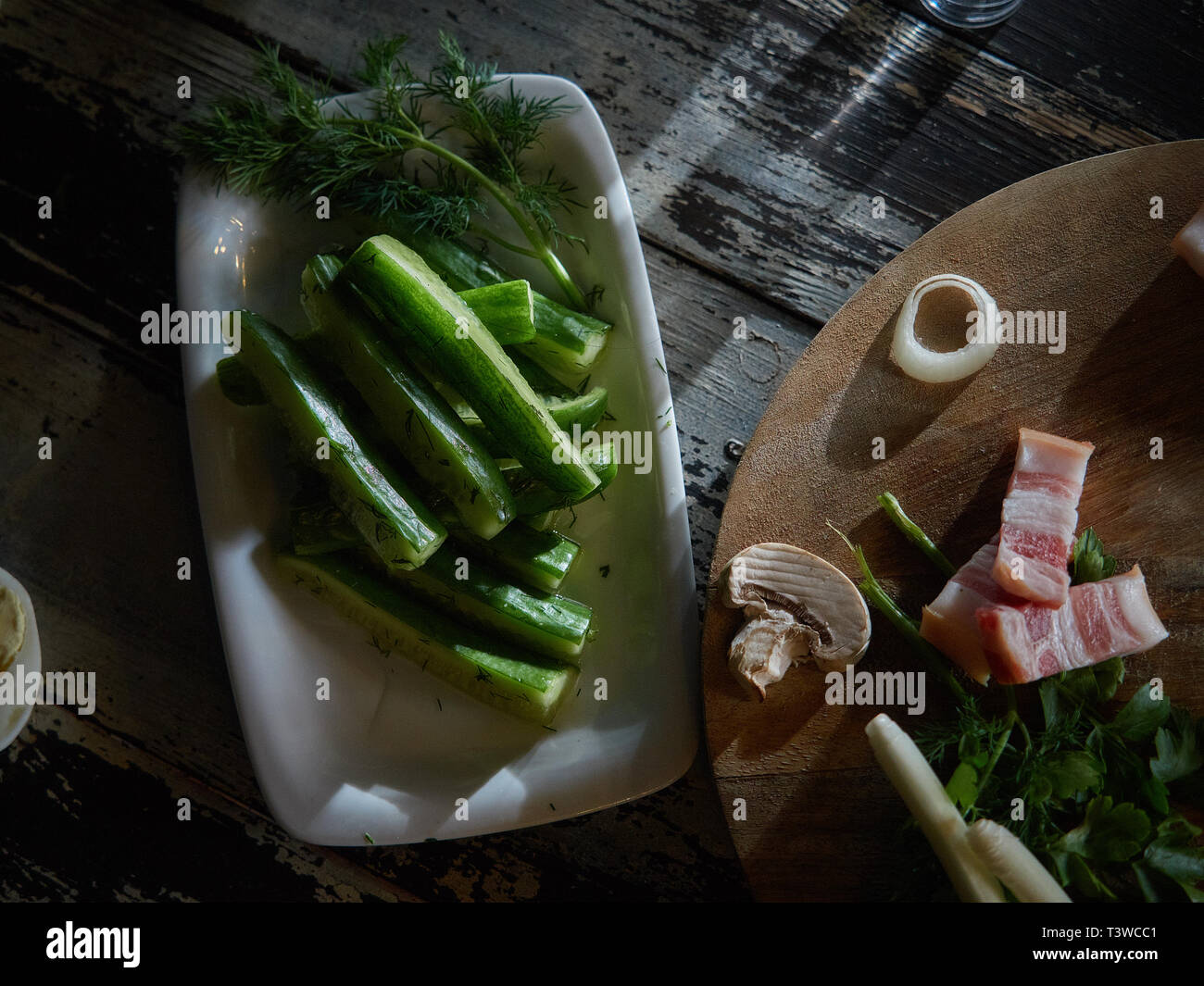 Fresche, bassa-coltivati cetrioli decorate con le cipolle verdi sono serviti. A una certa distanza, tagliare un paio di pezzi di carni suine fresche. Foto Stock