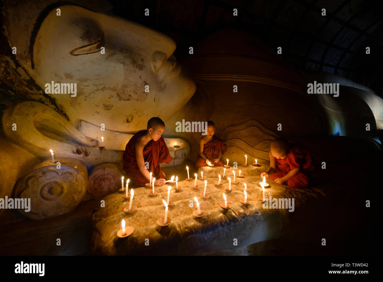 Monaci asiatici accendendo candele nel tempio Foto Stock
