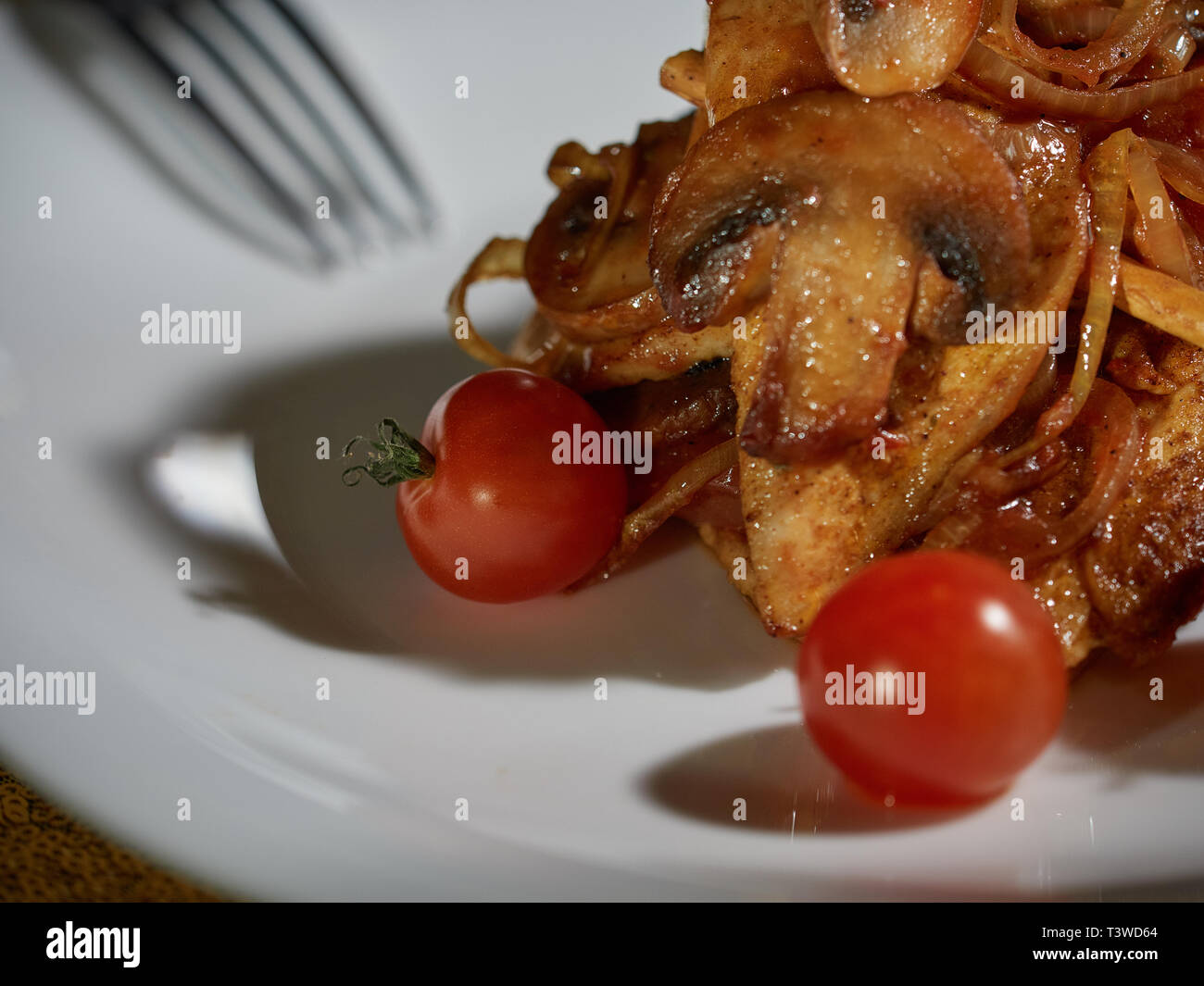 Piccoli tagli di carne cotta con funghi fritti e cipolle sono serviti a tavola per la cena. Foto Stock