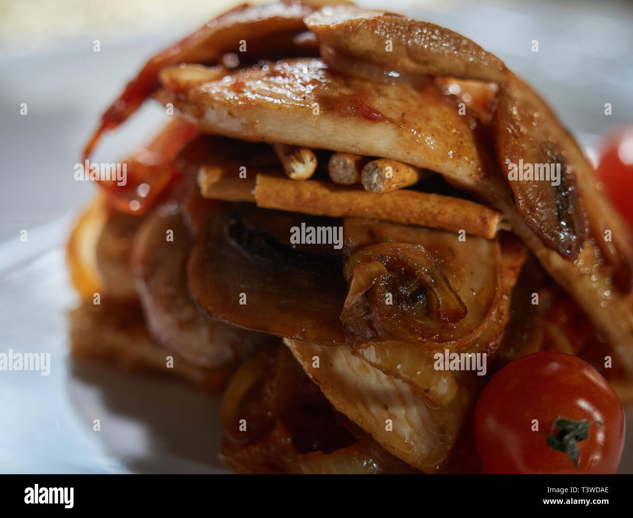 Piccoli tagli di carne cotta con funghi fritti e cipolle sono serviti a tavola per la cena. Foto Stock