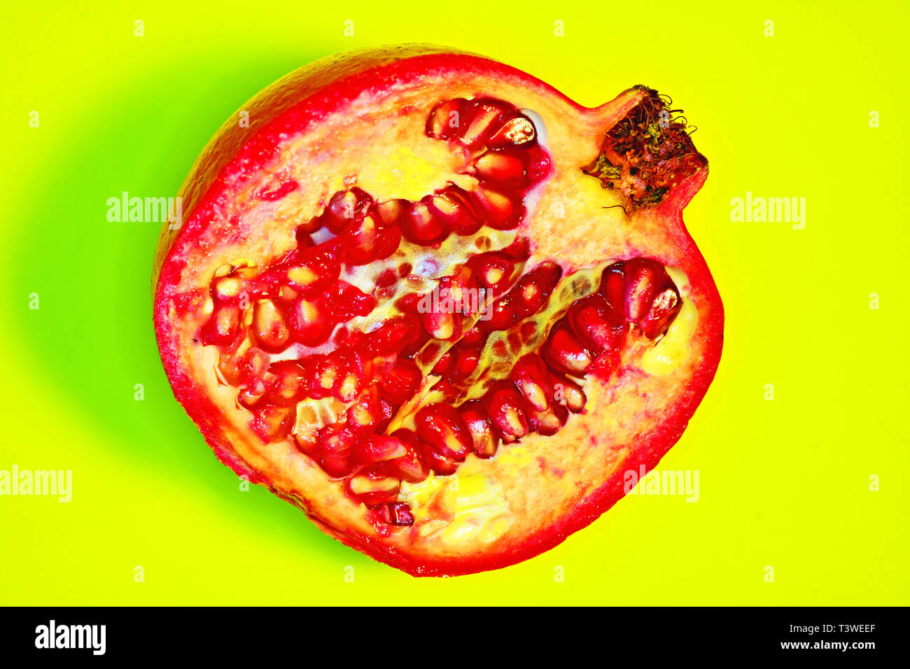 Un voluttuoso affettato e melograno rosso frutto seme contro lo sfondo di colore verde Foto Stock