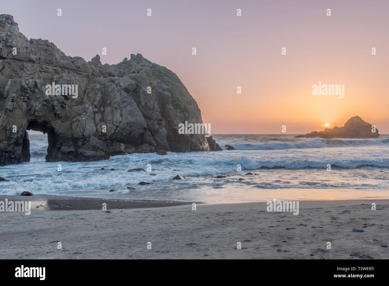 Lavaggio onde sulla spiaggia rocciosa al tramonto Foto Stock