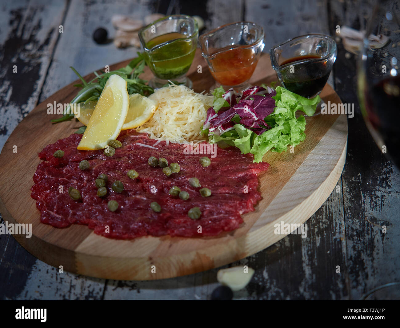 Un grande pezzo di materie di carni bovine è servita su un tavolo su un vassoio di legno con sughi di carne. Foto Stock
