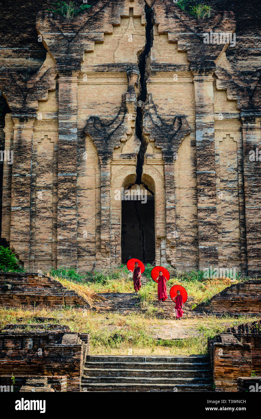 Monaci asiatici in piedi sotto gli ombrelloni vicino tempio storico, Mingun, Mandala, Myanmar Foto Stock