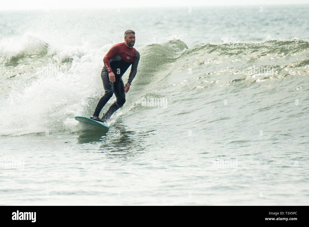 Aberystwyth, Wales, Regno Unito. 12 aprile 2019. Regno Unito: Meteo Surfers cattura le onde in corrispondenza della bocca del porto in una bella anche se coperto aprile primavera nel pomeriggio in Aberystwyth su Cardigan Bay costa del Galles occidentale. Credito: Keith Morris/Alamy Live News Foto Stock