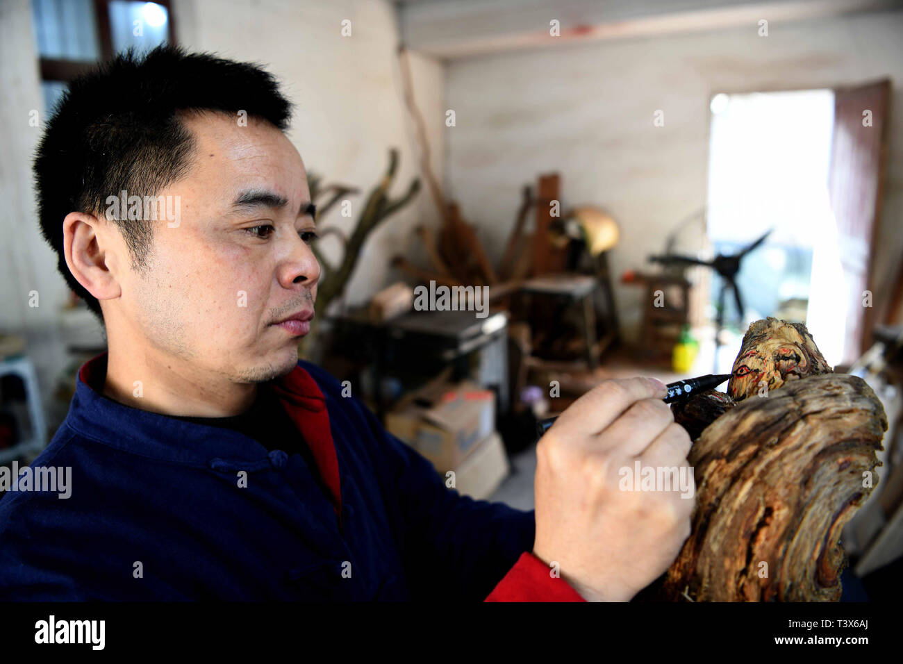 (190412) -- JINGXIAN, 12 aprile 2019 (Xinhua) -- 45 enne Ding Yonggang, un ereditiere di intaglio del legno, lavora su un pezzo di legno nella contea di Jingxian, est cinese della provincia di Anhui, 12 aprile 2019. Influenzato dagli anziani che sono impegnati nella lavorazione del legno, Ding ha sviluppato un forte interesse per le tradizionali tecniche di scultura sin dalla sua infanzia. Dopo anni di apprendimento e di pratica, Ding Yonggang è andata maturando nella sua abilità di sculture in legno e ha creato un gran numero di sculture in legno di opere d'arte. Sotto Ding il coltello, materie prime come alcuni umili rami e radici sono dotati con artistiche Foto Stock
