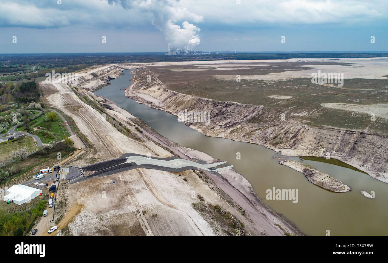 Cottbus, Germania. 12 apr 2019. Vista sull'ex miniera di lignite Cottbus-Nord. Tutta la terra di massa sul lato destro della foto sarà successivamente coperta dall'acqua. Sullo sfondo il vapore delle torri di raffreddamento di Jänschwalde alimentato a lignite impianto di alimentazione può essere visto. Presso l'ex Cottbus-Nord miniera a cielo aperto, l'acqua viene ruotata fino alla sera: il cosiddetto del Mar Baltico deve essere creato da allagare l enorme buca. Il grande lago artificiale avrà una zona di acqua di poco al di sotto dei 19 chilometri quadrati. Credito: dpa picture alliance/Alamy Live News Foto Stock