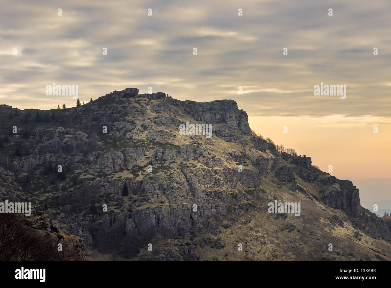 Rocky, picco soleggiato sulla vecchia montagna coperta da giallo erba e muschio sotto un colorato, cielo molto nuvoloso Foto Stock