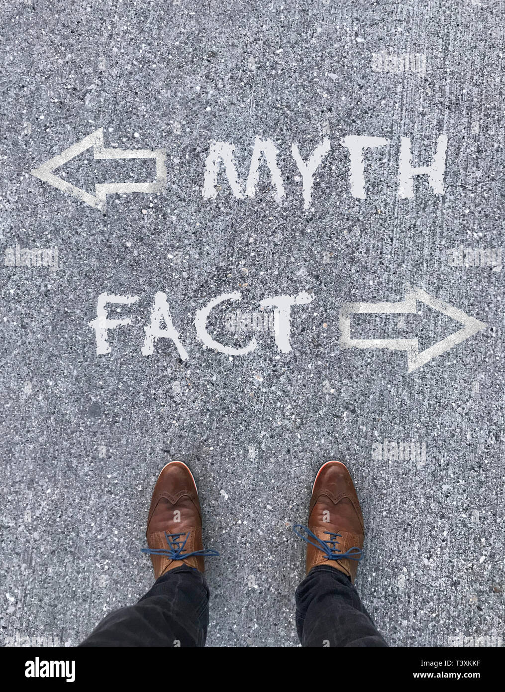 Uomo in piedi di fronte a due frecce e le parole 'mito' e 'Fatto' Foto Stock