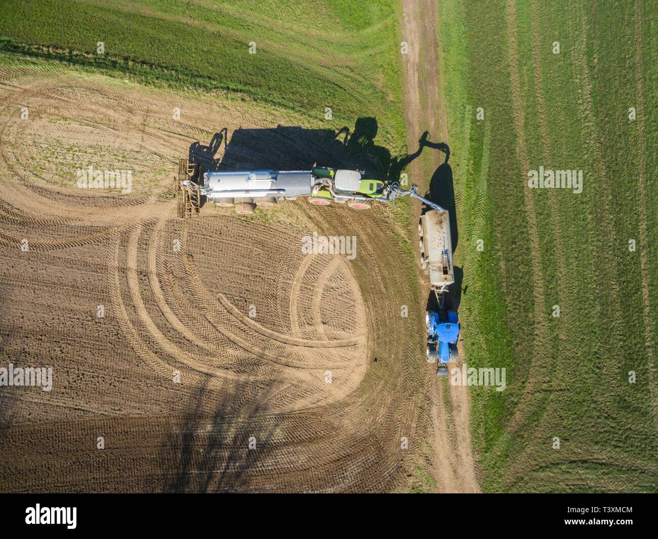 Vista aerea di un trattore con un moderno rimorchio di fertilizzante e un secondo trattore con un fertilizzante liquido il rimorchio su un campo agricolo Foto Stock