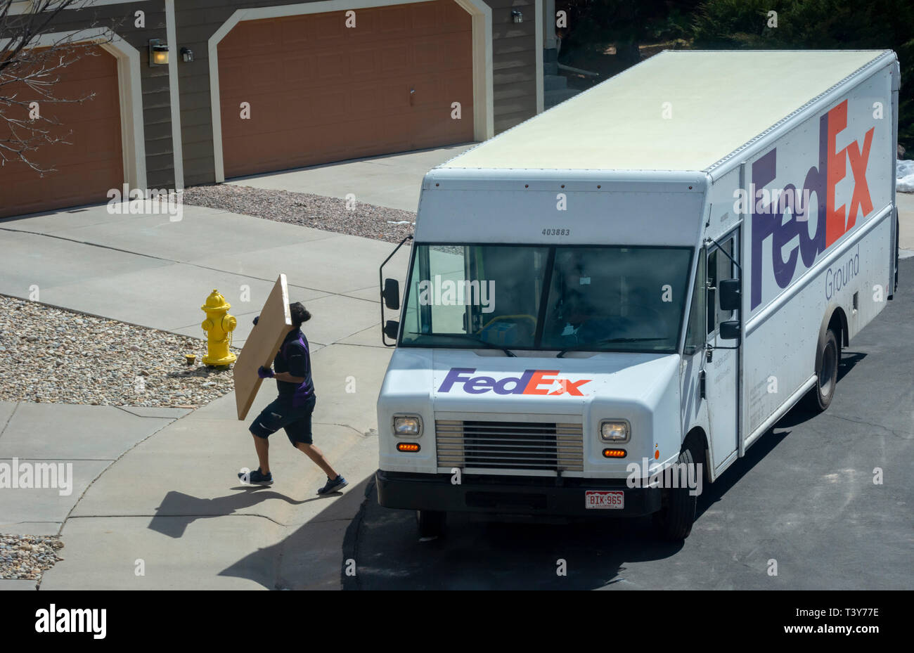 Federal Express delivery truck driver e pacchetto porta a casa residenziale, Castle Rock Colorado US. Foto scattata a marzo. Foto Stock