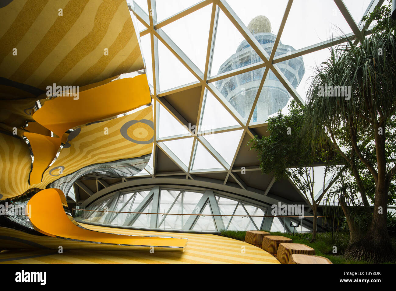 Uno scivolo giallo arancione contro la torre di controllo dell'aeroporto di Changi, Jewel Changi Airport. Singapore. Foto Stock