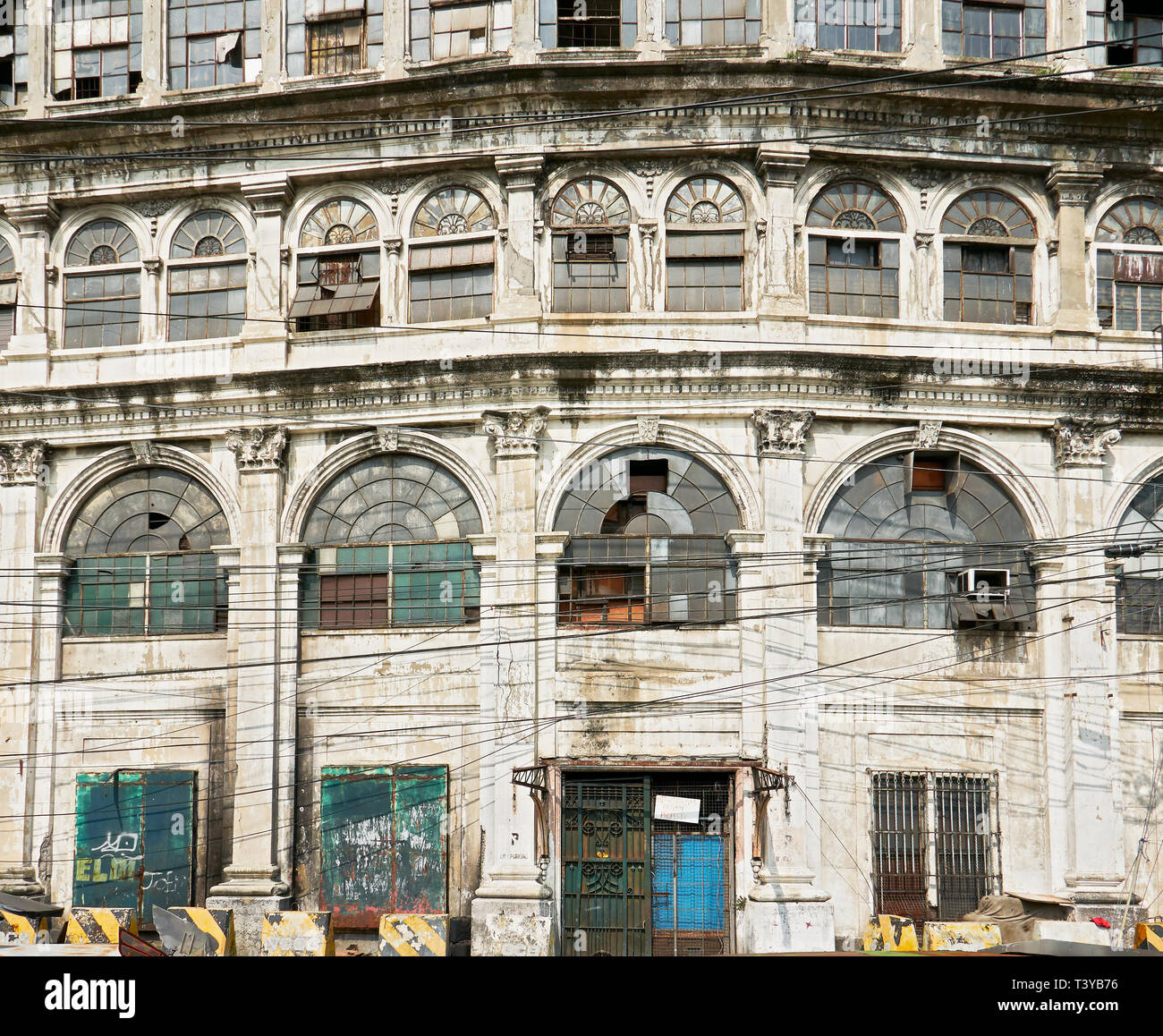 Facciata di un vecchio abbandonato spagnolo edificio commerciale con linee di alimentazione nella parte anteriore, in Escolta, Binondo, vicino al fiume Pasig, Manila, Filippine Foto Stock