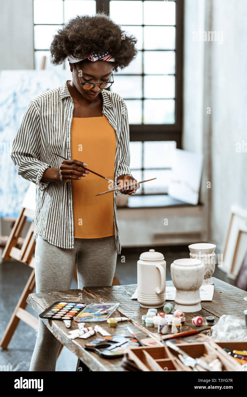 Uno studente d'arte. Giovani afro-americano di art student in piedi vicino alla tabella scegliendo acquerello Foto Stock