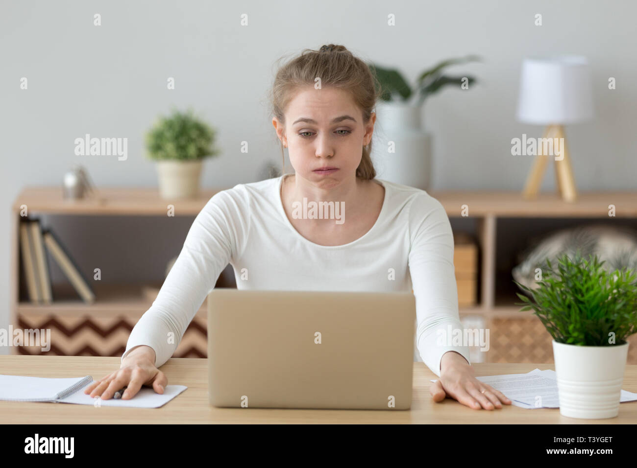 Confuso donna guardando lo schermo del notebook, facendo del difficile lavoro del calcolatore Foto Stock