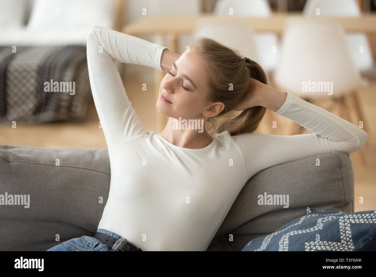 Felice donna calma rilassante e si estende su un comodo divano a casa Foto Stock