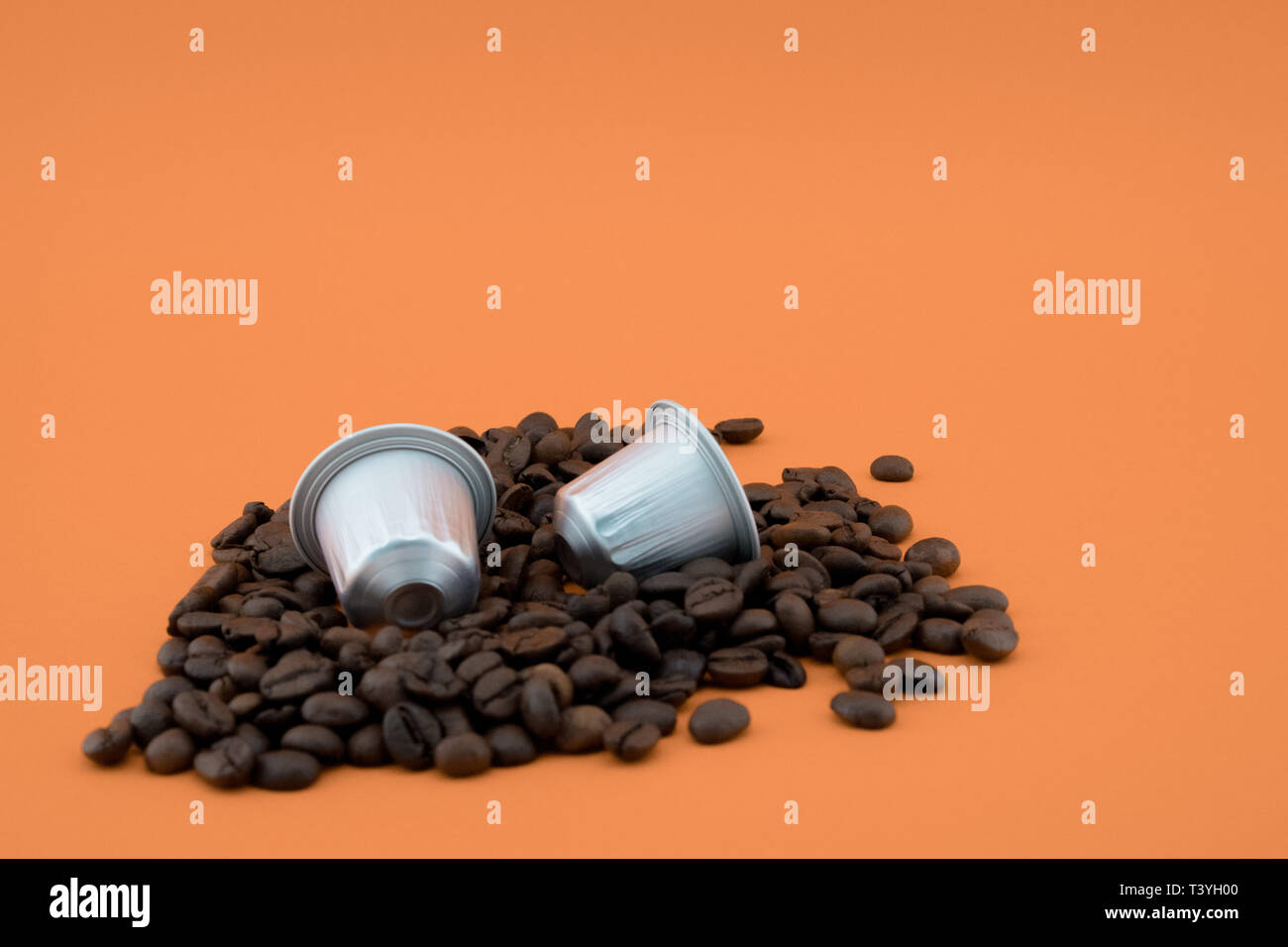 Caffè Espresso capsule o cialde di caffè in chicchi di caffè, sfondo arancione. Capsule per macchina da caffè. Foto Stock