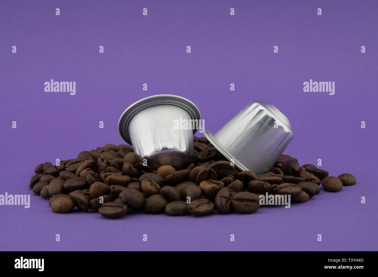 Le capsule di caffè o cialde di caffè in chicchi di caffè, sfondo viola. Capsule per macchina da caffè. Foto Stock