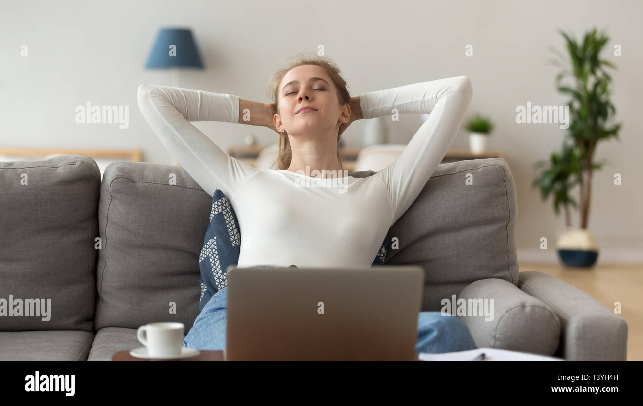 Donna pacifica stretching dopo la fine lavori al computer sul divano accogliente Foto Stock