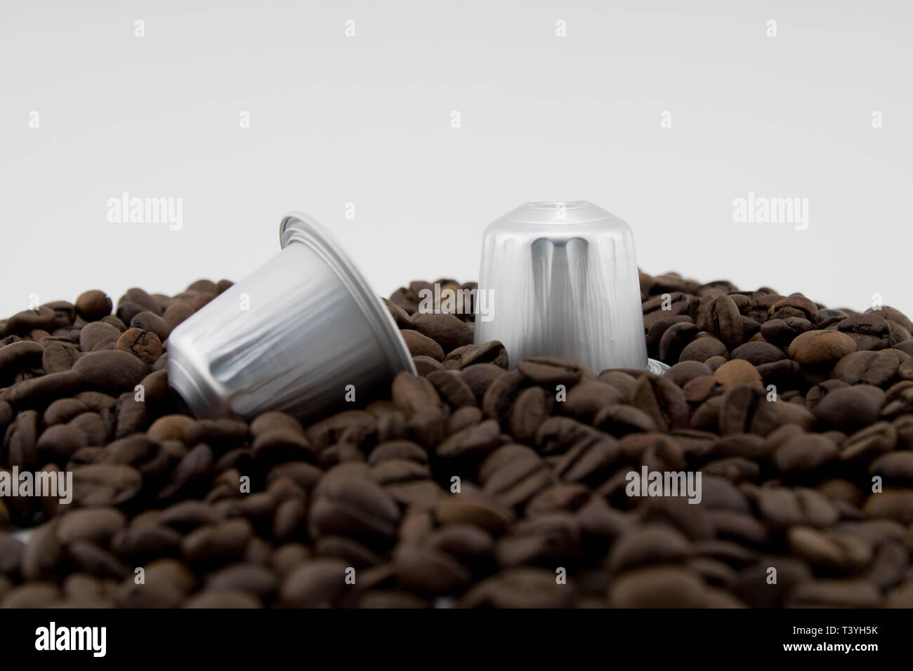 Le capsule di caffè o cialde di caffè in chicchi di caffè, sfondo bianco. Capsule per macchina da caffè. Foto Stock