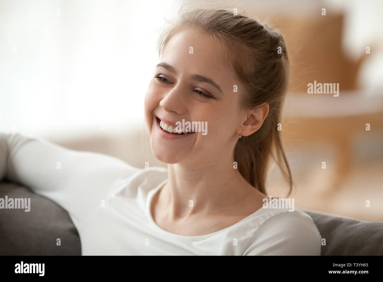 Close up sorridendo felice donna seduta nel salotto, divertendosi Foto Stock