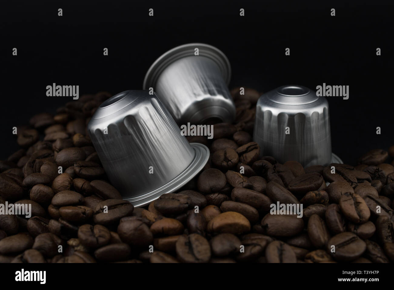 Il caffè italiano capsule o cialde di caffè in chicchi di caffè, sfondo nero. Capsule per macchina da caffè. Foto Stock