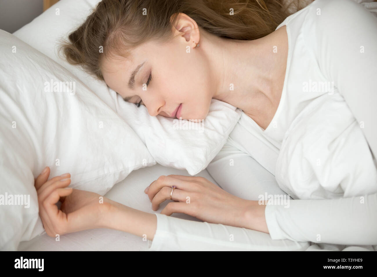 Close up calma pacifica giovane donna che dorme nel letto confortevole Foto Stock