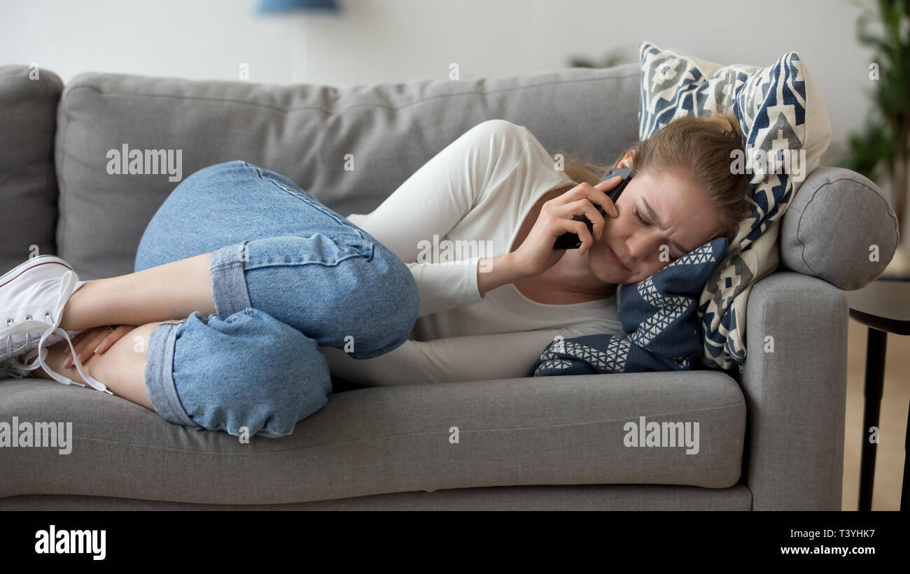 Frustrati donna disteso sul lettino, parlare al telefono, audizione cattive notizie Foto Stock