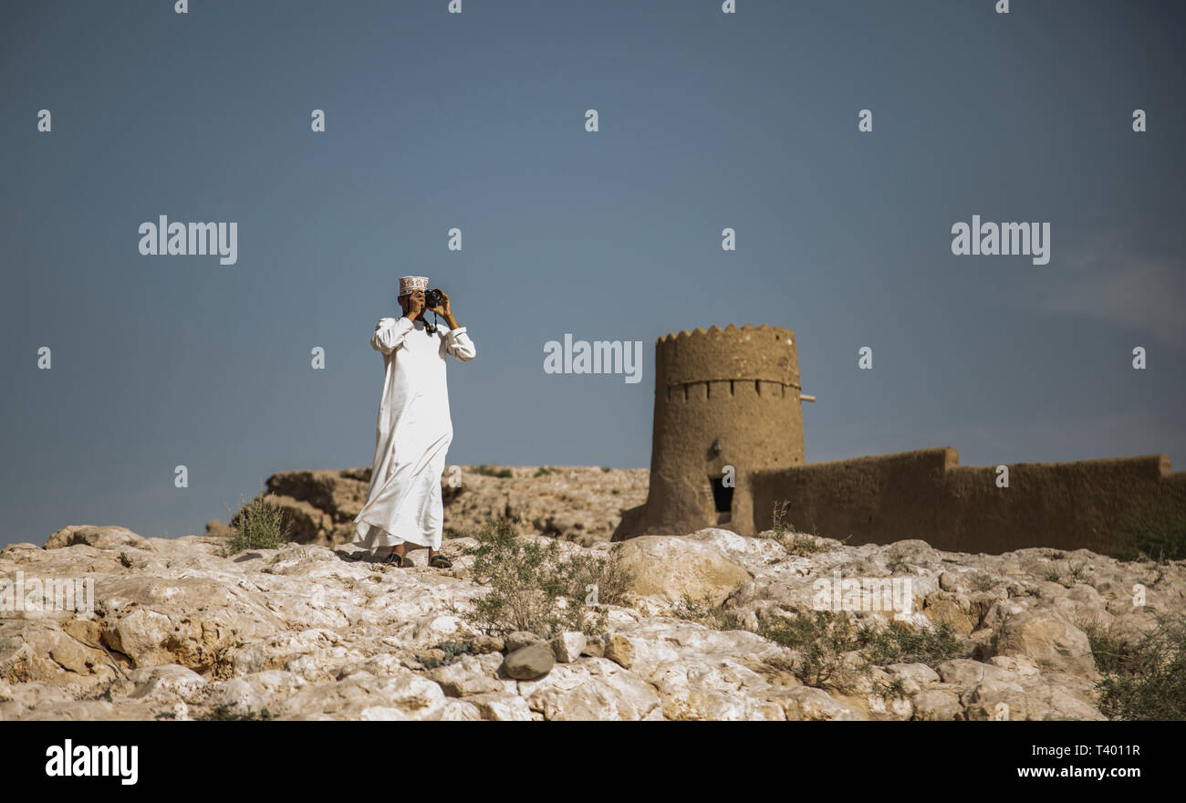 Al Sulaif, Oman, 9 Aprile 2016: omani uomo a fotografare le rovine di Al castello Sulaif Foto Stock