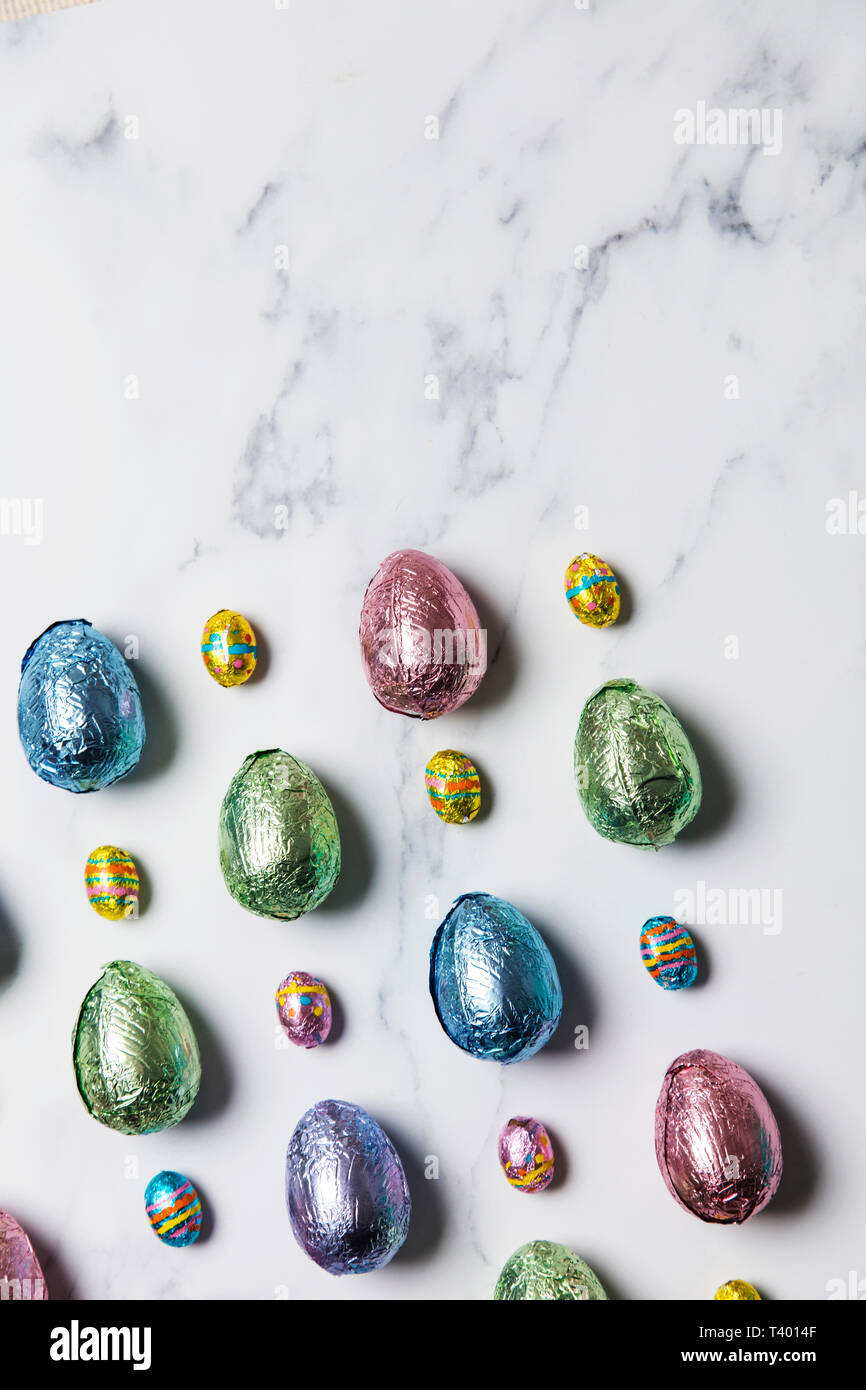 Uovo di Pasqua tratta di cioccolato avvolto in lucido foglio colorato su Sfondo marmo Foto Stock