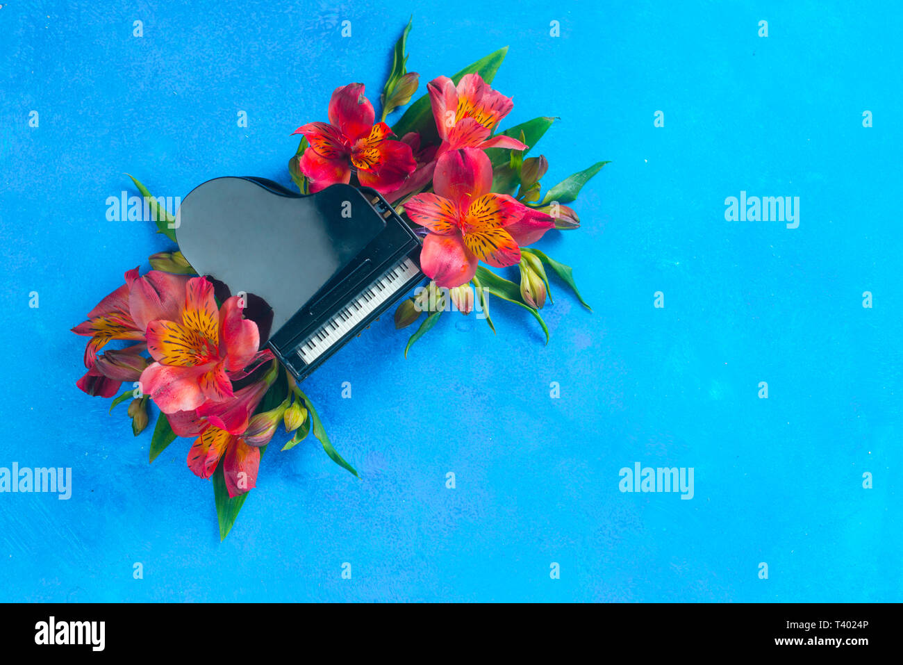 Piccolo pianoforte con molla alstroemeria fiori su uno sfondo blu con copia spazio. Primavera o estate festival musicale di concetto con spazio di copia Foto Stock