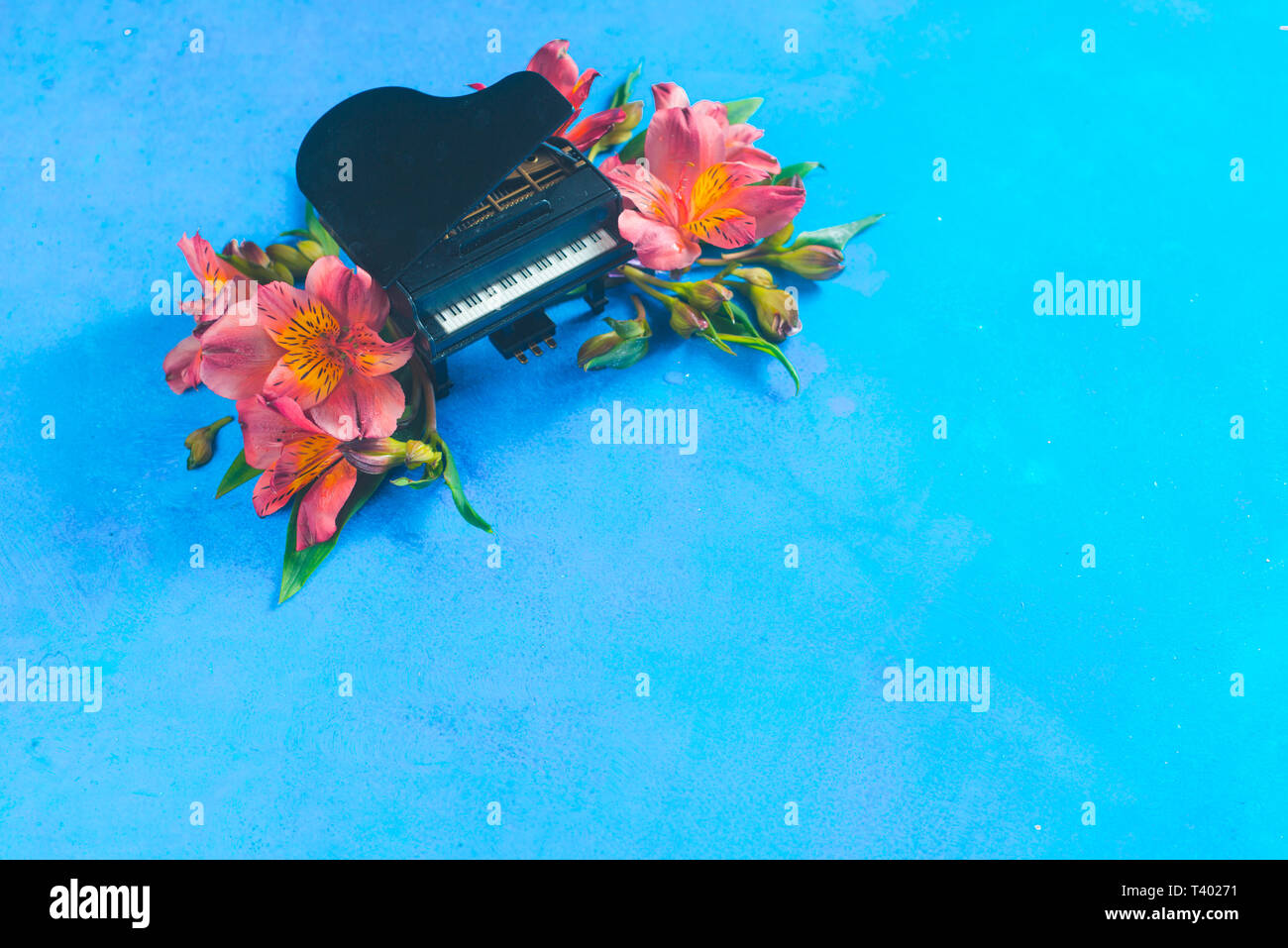 Piccolo pianoforte con molla alstroemeria fiori su uno sfondo blu con copia spazio. Primavera o estate festival musicale di concetto con spazio di copia Foto Stock