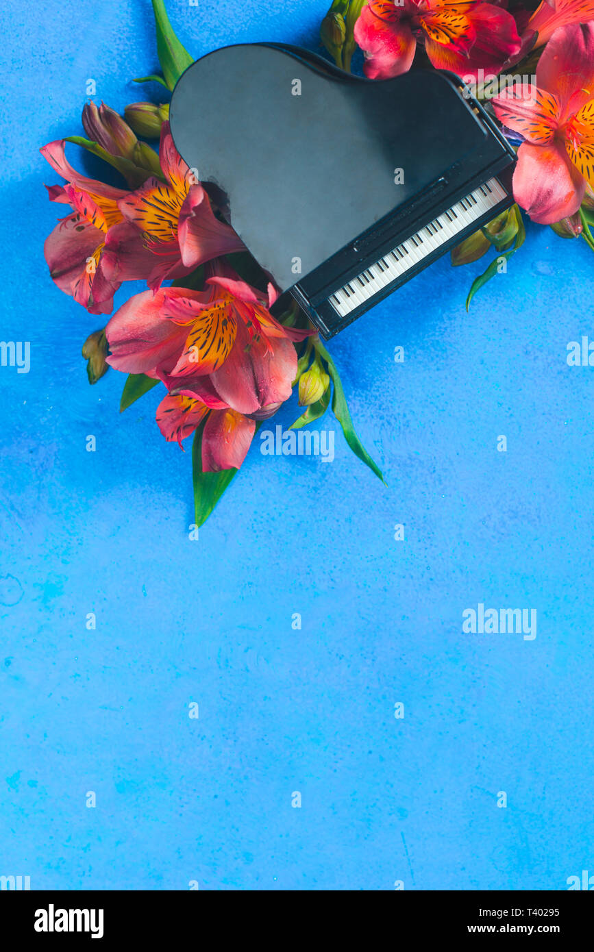 Piccolo pianoforte con molla alstroemeria fiori su uno sfondo blu con copia spazio. Primavera o estate festival musicale di concetto con spazio di copia Foto Stock