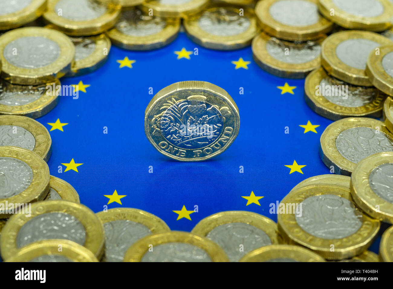 LONDON, Regno Unito - Aprile 2019: Vista ravvicinata della valuta britannica GBP - una sterlina moneta equilibrio sul suo bordo al centro del logo dell'Unione europea. Foto Stock