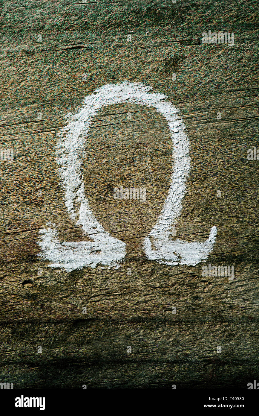 Primo piano di una lettera omega dipinta con gesso su un rustico di una superficie di legno Foto Stock