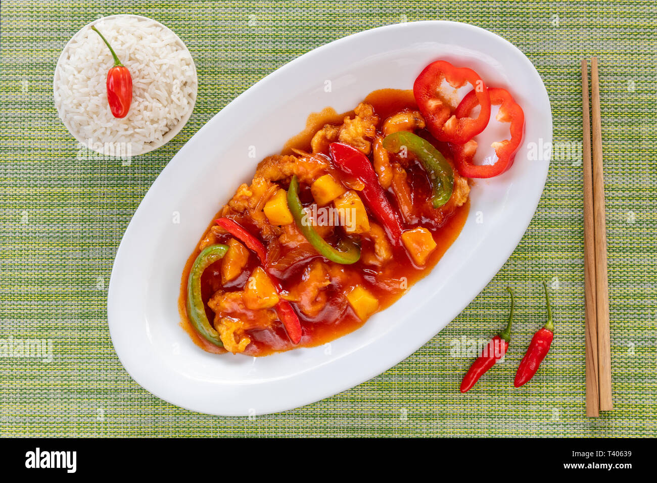 Il vietnamita in agrodolce pollo con ananas e peperoni servita con riso. Bacchette di legno e calce fresca sul lato. Vista dall'alto. Foto Stock