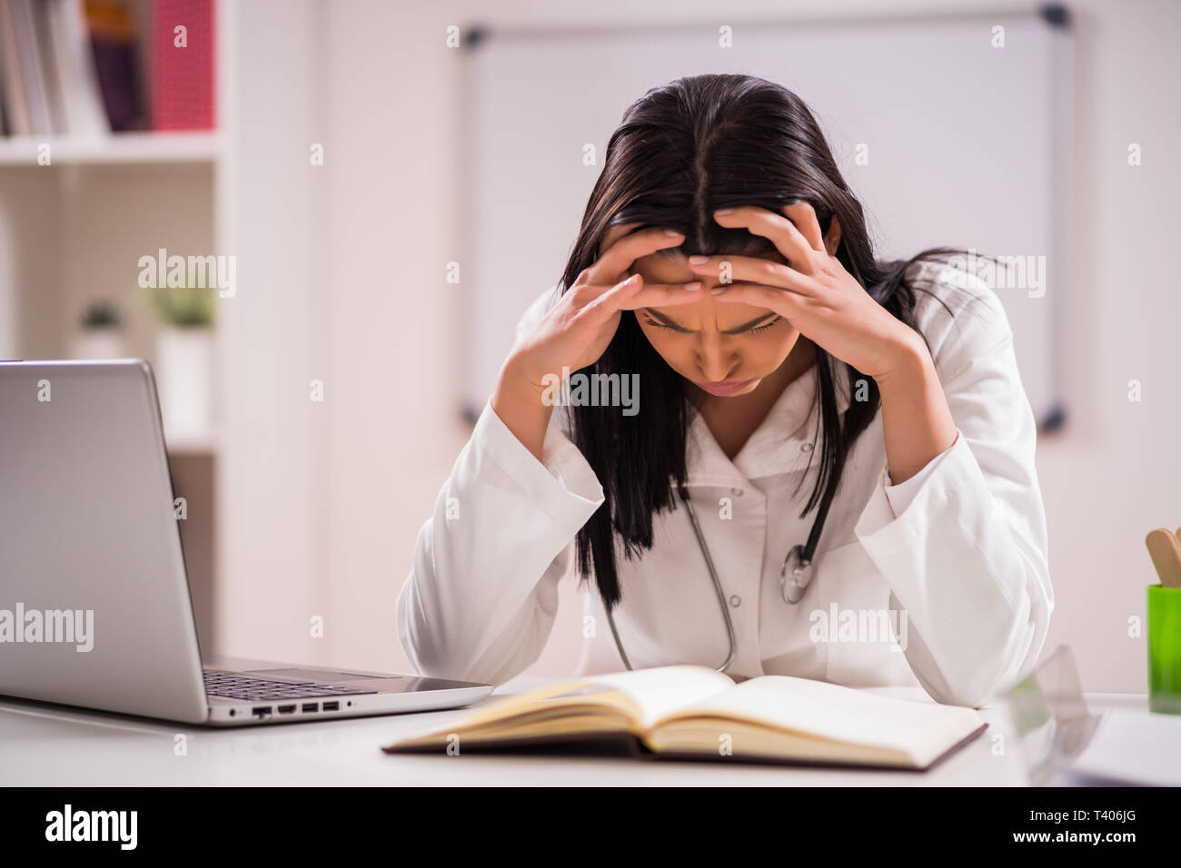 Giovane medico è stanco. Ha mal di testa nel suo ufficio. Foto Stock