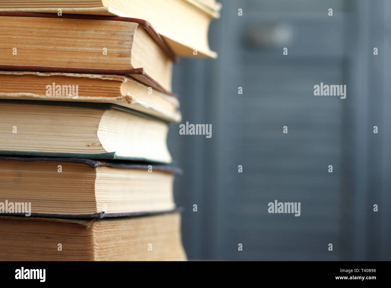 Una pila di libri d'epoca per il business e l'istruzione su una superficie di legno contro un muro bianco, torna al concetto di scuola. Foto Stock