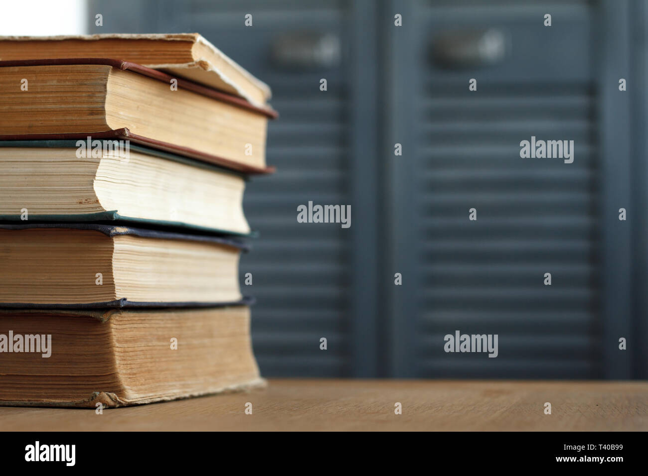 Una pila di libri d'epoca per il business e l'istruzione su una superficie di legno contro un muro bianco, torna al concetto di scuola. Foto Stock