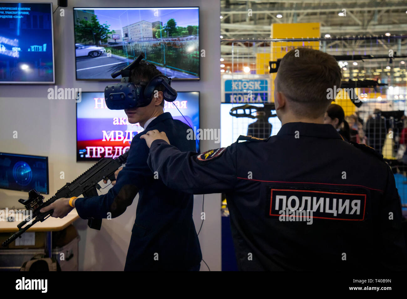 Un funzionario di polizia aiuta il visitatore sulla realtà virtuale simulatore per le forze di polizia delle forze speciali presso lo stand del Nizhny Novgorod Accademia di polizia Foto Stock