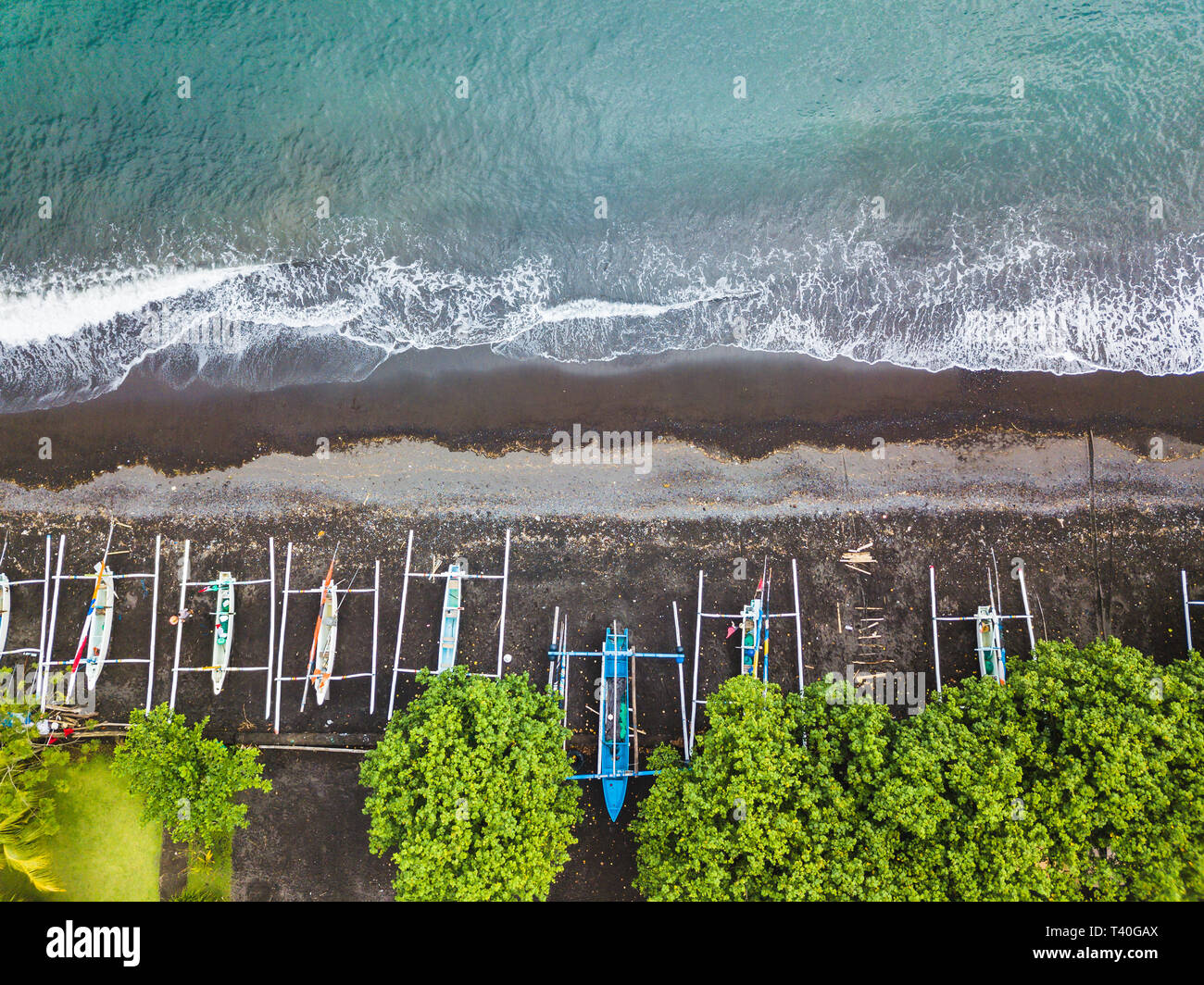 Top down vista aerea di Indonesiani tradizionali barche da pesca chiamato jukung sulla spiaggia di sabbia nera. In Amed, Bali, Indonesia. Foto Stock