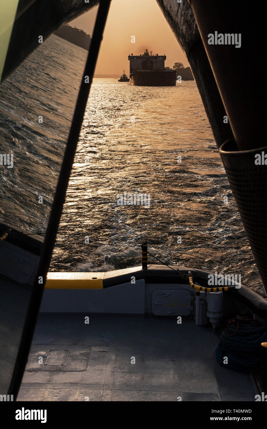 Sunrise durante le operazioni portuali la gestione ed il trasporto di minerale di ferro. Da nave a nave il funzionamento in movimento dal leader di tirare per tirare e TSV nel canale di spedizione Foto Stock