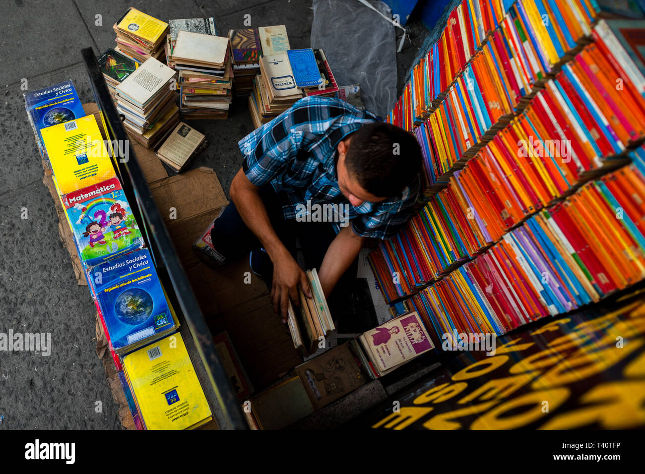Un libraio di Salvadoran pile di libri in pile sulla strada in una libreria di seconda mano in San Salvador El Salvador. Foto Stock